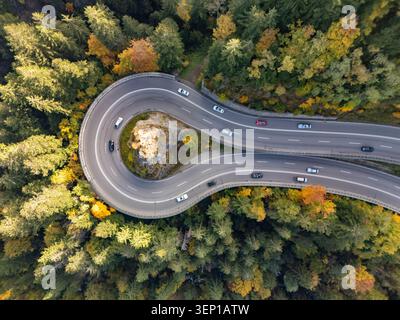 Aus der Vogelperspektive einer Haarkurve auf der Bergstraße mit einem Kreuz auf dem Felsen im Herbst Stockfoto