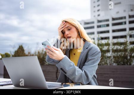Eine junge Frau, die schlechte Nachrichten auf ihrem Telefon erhält, fühlt sich besorgt Stockfoto