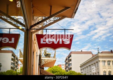Batumi, Georgia - 09. Juni 2026: Red Levi's Logo-Schild hängt an einer Gebäudefassade vor einer Modeboutique vor dem Himmel und der Stadt. Stockfoto