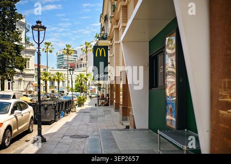 Batumi, Georgia - 9. Juni 2026: Malerische Stadtlandschaft mit Blick auf die Straße mit Palmen und einem Markenschild von McCafé und McDonald's. Stockfoto