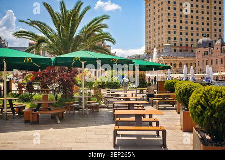 Batumi, Georgia - 9. Juni 2026: McDonald's Terrasse im Freien mit grünen Sonnenschirmen und Palmen. Stockfoto