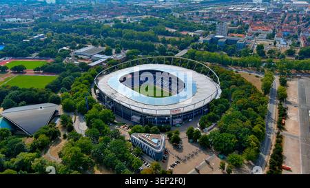 Drohnenansicht des Stadions Heinz-von-Heiden-Arena Hannover 96 mit blauen Sitzen umgeben von Parklandschaft, Deutschland Stockfoto