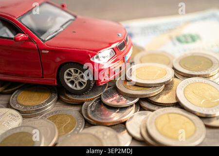 BANGKOK, THAILAND - 12. FEBRUAR 2023, Auto auf Münzen Hintergrund; Autokredit, Finanzen, Sparen, Versicherung und Leasingzeit Konzepte. Stockfoto