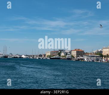 Ein sonniger Nachmittag über dem ruhigen Adriakanal in Zadar, mit historischer Architektur, modernen Gebäuden und vielen verankerten Booten. Stockfoto