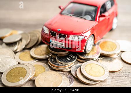 BANGKOK, THAILAND - 12. FEBRUAR 2023, Auto auf Münzen Hintergrund; Autokredit, Finanzen, Sparen, Versicherung und Leasingzeit Konzepte. Stockfoto