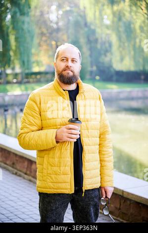Gentleman mit Brille. Mann in gelbem Blazer in der Nähe von Wasser. Männliche Figur mit Brille und nahem Ausdruck. Individual trug gelbe Jacke neben Wasser mit freundlicher Einstellung Stockfoto