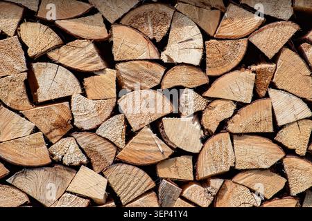 Nahaufnahme von sauber gestapeltem Brennholz mit natürlicher Holzstruktur und organischen Texturen. Rustikaler Hintergrund symbolisiert Nachhaltigkeit, traditionell Stockfoto