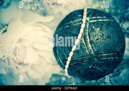 Vintage Hintergrund mit rosa Pfingstrose, Juwelen und alter rostiger Eisenkugel auf der Spitze. Veraltetes Foto. Stockfoto