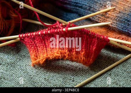 Buntes Strickprojekt mit Stricknadeln und Wollgarn im Gange Stockfoto