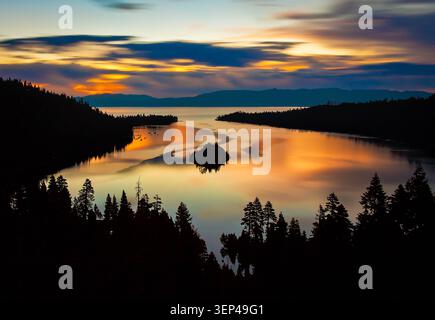 Ruhiger Sonnenuntergang Über Dem See Mit Silhouetten Der Kleinen Insel Und Des Waldes, Die Sich Im Ruhigen Wasser Spiegeln Stockfoto