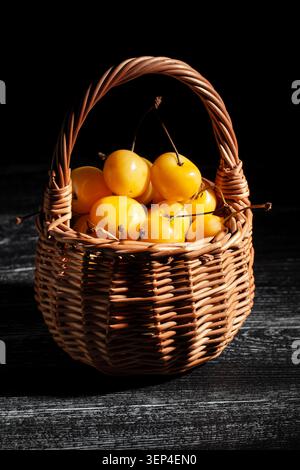 Gelber Kirschkorb auf schwarzem Holzhintergrund Stockfoto