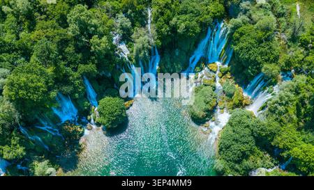 Blick aus der Vogelperspektive auf den Kravica Wasserfall, umgeben von üppigem Wald und smaragdgrünem Wasser in Herzegowina, mit einem malerischen Naturdenkmal im Sommer Stockfoto