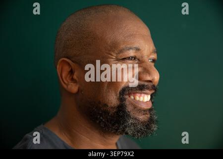 Afroamerikaner reifer Mann lächelt, während er im Studio-Porträt mit dunkelgrauem T-Shirt blickt Stockfoto