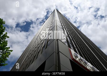 Niedriger Blick auf den modernen Wolkenkratzer aus Glas und Stahl vor dem dramatisch bewölkten blauen Himmel Stockfoto