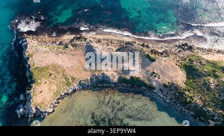 Dieses atemberaubende Stockbild fängt die Luftperspektive einer felsigen Küste mit kristallklarem türkisfarbenem Wasser ein. Die Landschaft verfügt über einen robusten cl Stockfoto