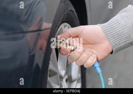 Prüfen des Reifendrucks mit dem Luftschlauch an der Servicestation. Fahrzeugwartung und Verkehrssicherheitskonzept für Fahrer. Stockfoto