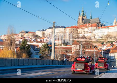 Prag, Tschechische Republik, 27. Dezember 2025, Ein malerischer Blick auf Prag, Tschechische Republik, mit zwei Vintage-Stil-roten Cabriolets, die über eine Bride fahren Stockfoto