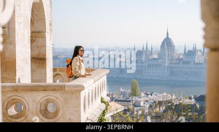 Budapest, Ungarn, bietet atemberaubende Panoramen von der Fischerbastei. Ein Reisender blickt über die atemberaubende Stadtlandschaft und fängt die Schönheit des ikonischen Parlamentsgebäudes auf der anderen Seite des Flusses ein. Stockfoto