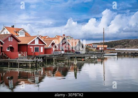 Bezauberndes rotes Ferienhaus mit weißer Zierleiste und gekacheltem Dach in einer ruhigen Küstensiedlung Stockfoto