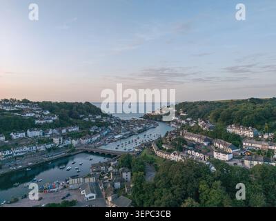 Blick auf die Stadt Looe aus der Vogelperspektive, eingebettet in ein steiles Tal, das bei Sonnenaufgang zum Meer führt, zeigt die Brücke über die Flussmündung Stockfoto