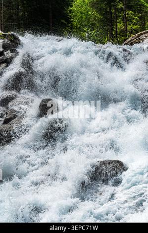 Vertikales Foto eines mächtigen Bergwasserfalls in Pfelders, Südtirol, Italien. Schäumende Wildwasser-Stromschnellen rasen über dunkle Felsen und füllen den fram Stockfoto