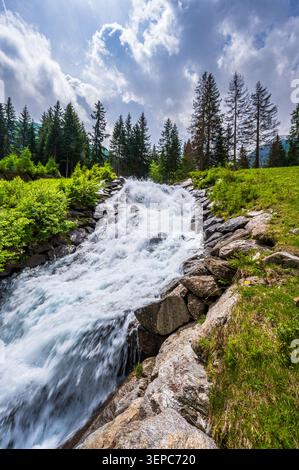 Dynamischer alpiner Wasserfall, der bei hellem Tageslicht über Felsen bei Pfelders in Südtirol, Italien, rauscht. Der mächtige Strom fließt durch einen felsigen Kanal Stockfoto