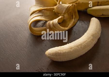 Frisch Geschälte Banane Auf Holztisch Mit Bananenschale Und Kopierraum Stockfoto