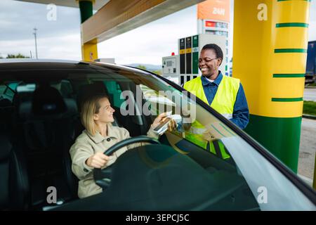 Frau, die für Gas bezahlt, indem sie kontaktlos am Bahnhof bezahlt Stockfoto