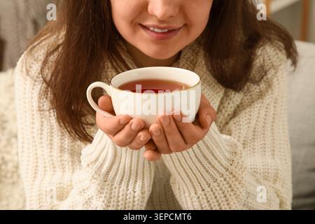 Gemütliche Frau mit warmer Teetasse in Strickpullover, Komfort und Entspannung zu Hause, Wellness und Selbstpflege Stockfoto