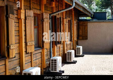 Rustikale Holzfassade mit offenen Fensterläden und mehreren Klimaanlagen im Freien Stockfoto