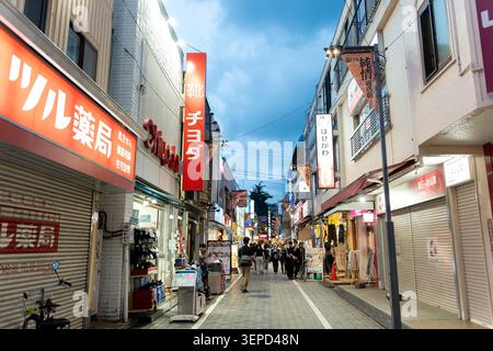 Fußgänger, die durch die Einkaufsstraße Koenji Junjo laufen, gesäumt von Geschäften und Schildern in der Abenddämmerung, Koenji, Suginami, Tokio, Japan, 14. Juni 2026 Stockfoto