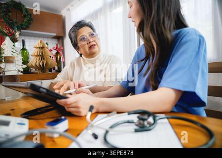 Ernsthafte ältere asiatische Frau Beratung Krankenschwester Tablet-Technologie, professionelle Pflegekraft Notizen Tablett Seniorin sprechen, Service Assistentin el Stockfoto