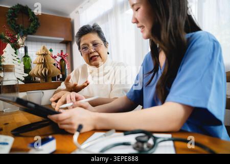 Ältere asiatische Frau erklärt Symptome Krankenschwester Schreiben Tablette, Home Care Krankenschwester hören ernste reife Dame Tablette Beratung, diskutieren Gesundheit Stockfoto