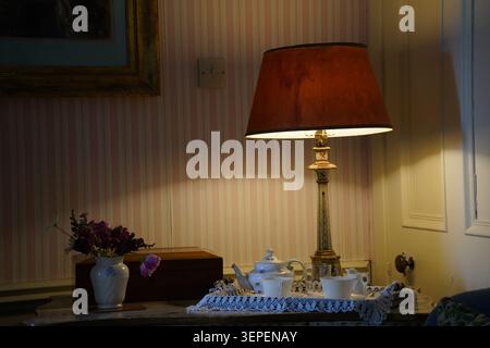 Ein gemütliches Vintage-Teeset unter einer warmen Tischlampe Stockfoto