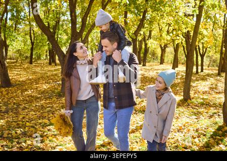 Eltern und Kinder genießen einen spielerischen Spaziergang durch den Herbst Park mit goldenem Laub Stockfoto