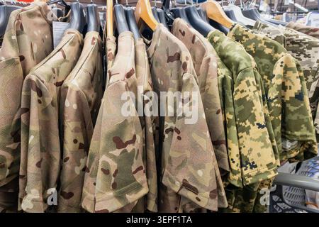 Militärische Tarnuniformen auf Kleiderbügeln für Armee, Verteidigung und Taktische Ausrüstung auf dem Markt. Nahaufnahme. Stockfoto