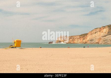 Ein malerischer Blick auf die Küstenpromenade und die dramatischen Klippen am Strand in der Küstenstadt Nazaré, Portugal. Stockfoto