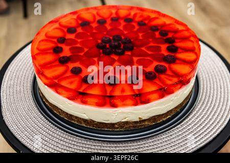 Erdbeer-Gelee-Käsekuchen mit frischen Erdbeeren und Heidelbeeren, cremiger Füllung und knuspriger Keksbasis. Stockfoto