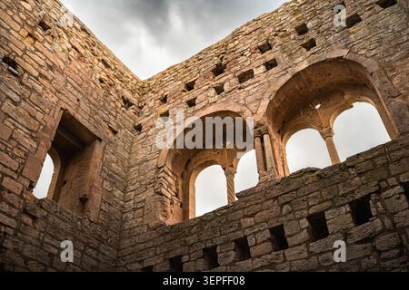 Detaillierte architektonische Fotografie von mittelalterlichen Steinbögen und Säulen innerhalb der historischen Burgruine, aufgenommen aus einem niedrigen Aufwärtswinkel Stockfoto