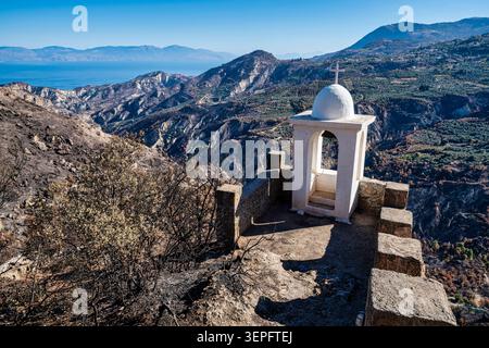Weißer Glockenturm der Panagia Katafigiotissa Kapelle auf einer Klippe über dem Tal bei Zacholi, Korinthia, Griechenland, ideal für Religion, Reisen, Sie Stockfoto