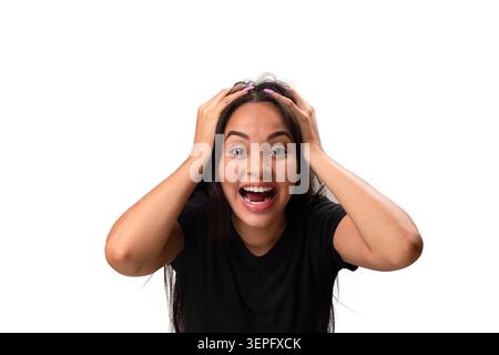 Schockierte und glückliche junge hispanische Frau mit offenem Mund, der den Kopf in den Händen hält und in die Kamera blickt. Eine große Überraschung, Aufregung oder Schock ausdrücken. Stockfoto