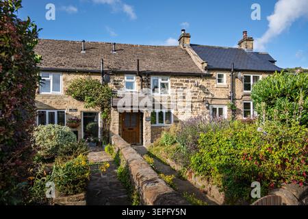 Breiter horizontaler Blick auf die traditionellen Steingebäude, die von alten Hüttengärten entlang des Causeway im historischen Dorf Eyam umgeben sind Stockfoto