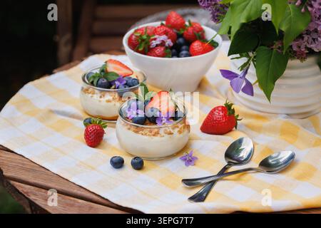 Cremiges Käsekuchen-Dessert mit frischen Beeren und essbaren Blumen Stockfoto