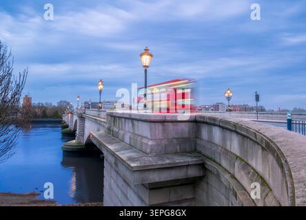 Langzeitbelichtung der historischen Putney Bridge über die Themse zur blauen Stunde mit einem roten Doppeldeckerbus, London, England Stockfoto
