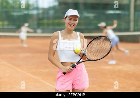 Porträt einer sportlichen Tennisspielerin mit Schläger und Ball in den Händen Stockfoto