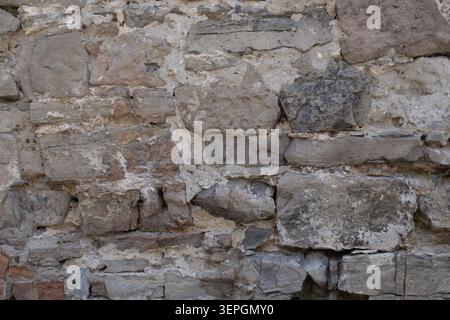 Alte Steinmauerwerk-Wandstruktur mit verwitterten Felsen und historischem architektonischen Muster Stockfoto
