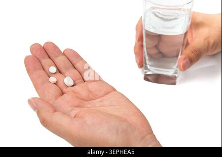 Nahaufnahme einer Person, die verschiedene medizinische Pillen auf Palme und ein Glas Wasser hält, Gesundheitskonzept. Stockfoto