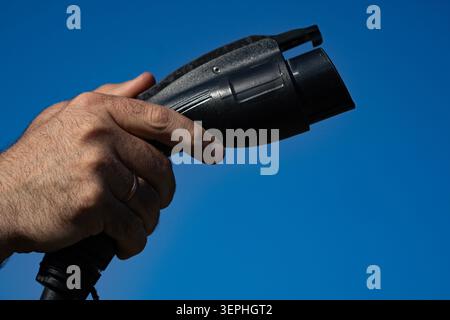 Kabelgriff zum Anschluss des elektrischen Ladegeräts. Das Ladekabel versorgt die Fahrzeugbatterie. Die Kabelnähe zeigt Fahrzeugausrüstung. Kabelanschluss versorgt EV Stockfoto