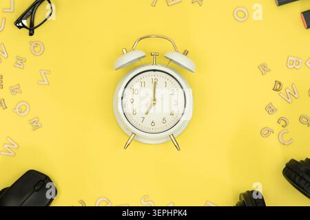Hintergrund zum Thema Bildung, Schulhintergrund. Wecker auf gelbem Hintergrund Draufsicht Stockfoto