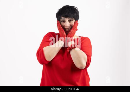 Fröhliche, große Frau, die ihre Wangen berührt, mit lächelnden Händen Stockfoto